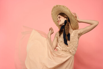 Fashionable woman in dress and hat with black ribbon on pink background cropped view of model emotions fun