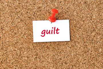 Wall Mural - Guilt. Word written on a piece of paper, cork board background.