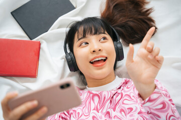 Young asian woman in pink shirt enjoy listen to music with headphone and smartphone.