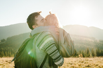 The daughter hugs and kiss father on nature. Dad with backpack and child walk in the autumn grass. Family spending time together in mountain on vacation. Holiday trip concept. World Tourism Day.