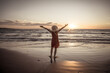© SB Arts Media - Woman in red with arms outstretched by the sea at sunrise enjoying freedom and life