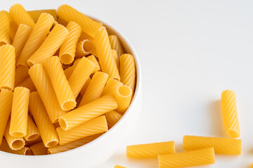 Raw dry uncooked Tortiglioni pasta spaghetti noodle on white bowl wooden background for basil tomato pesto sauce Homemade Italian food organic whole wheat vegan spaghetti for a healthy meal