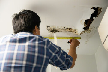 worker repair and fixing ceiling panels damaged hole in the roof house from pipes water leakage. off