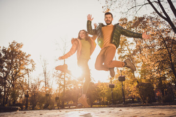 Poster - Low angle view full size photo of crazy positive girl guy fellows jump in autumn september city park