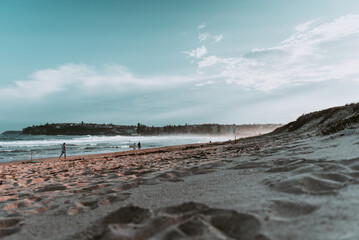 Sunset at the beach with clouds spread in the sky and calm waves of water of the ocean in the background