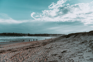 Sunset at the beach with clouds spread in the sky and calm waves of water of the ocean in the background