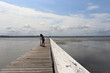 © Irene's Stock - Silhouette of young girl with dark hair alone enjoying rides on a scooter in this wooden jetty bridge. Skyline background in this quite lake landscape in the Central Coast Australia