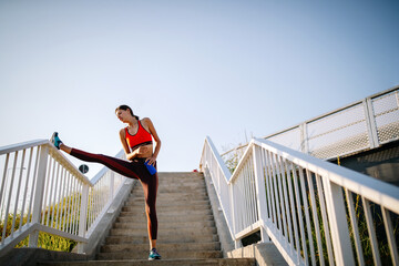 Wall Mural - Portrait of fit cheerful woman resting after a run in a city