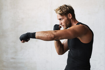 Photo of athletic young handsome boxer doing exercise while working out