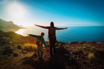 Wall Mural - silhouette of happy mother and son travel at sunset mountains