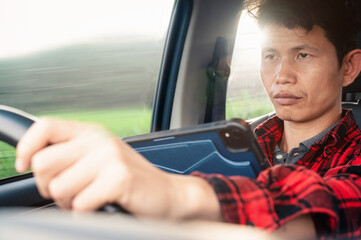 Poster - Man use tablet or phone while driving a car his looking on a device and road and steering a wheel and typing message ,Dangerous driving concept