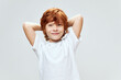 © SHOTPRIME STUDIO - Cheerful red-haired boy holding hands behind his head smile white t-shirt