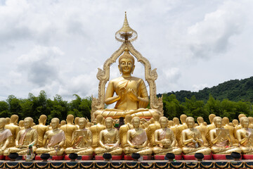 Golden Buddha statue on a mountain in the green forest.