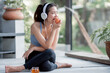 Healthy and Sportive woman eating apple and using headphone to listen music