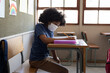 © Wavebreak Media - Boy wearing face mask writing while sitting on his desk at school
