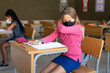 © Wavebreak Media - Girl wearing face mask sneezing while sitting on her desk at school
