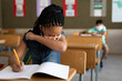 © Wavebreak Media - Girl wearing face mask sneezing while sitting on her desk at school