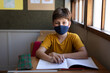 © Wavebreak Media - Portrait of boy wearing face mask sitting on his desk at school