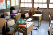 © Wavebreak Media - Group of kids wearing face masks writing while sitting on their desk at school