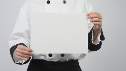 Wall Mural - Woman wearing chef uniform and holding A4 paper on white background.