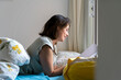 © VITTA GALLERY/Westend61 - Smiling woman reading from note pad in bedroom