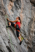 Confident Woman Climbing Rocky Mountain Using Rope