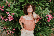 Close-up Of Smiling Mid Adult Woman With Curly Hair Standing Against Plants In Park