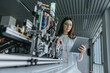 © Mareen Fischinger/Westend61 - Young woman using digital tablet while standing by machinery in laboratory