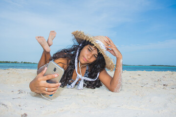 Wall Mural - African american ethnicity teenager using social media with mobile phone at tropical beach