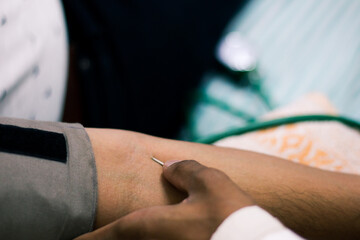 needle for blood collection inserted in arm of patient by attendant