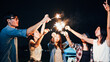 © Urbanscape - Group of young Asian college student friends lit light sparkler, sing and dance together at beach camping tent. Party people, love friendship relationship, or outdoor camping activity concept