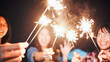 © Urbanscape - Group of young Asian college student friends lit light sparkler, sing and dance together at beach camping tent. Party people, love friendship relationship, or outdoor camping activity concept