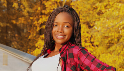 Portrait of young smiling african woman wearing sunglasses in autumn day