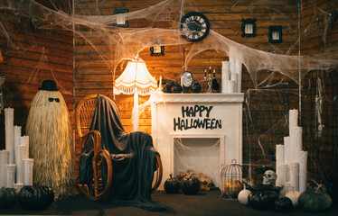 Photo of a Halloween decor with a fireplace and a rocking chair. Interior is decorated for Halloween, photozone. Background.