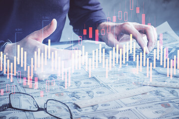 Double exposure of man's hands holding and using a digital device and forex graph drawing. Financial market concept.