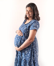 A Pregnant Indian Lady With Blue Dress And Hands On Belly.