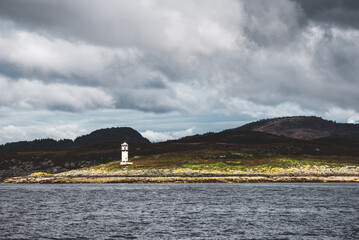 Wall Mural - Panoramic view of the rocky shores of Tarbert under dramatic sky. Lighthouse in the background, Scotland, UK. Travel destinations, national landmark, recreation, eco tourism, vacations