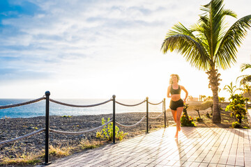 Wall Mural - Young fit woman run outdoor with ocean and sunset sunlight background - concept of people healthy lifestyle and exercise wotk out to stay slim and lost weight with exercises and jogging