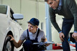 © Drazen - Female mechanic and customer examining car tire in auto repair shop.
