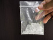 Hand holding amphetamine in plastic pack on black background. Dangerous drug. addictive substance. narcotic concept.