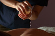 © bander - Hands of masseuse applying coconut oil on a back of a client