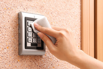 Woman using tissue paper to press keys of digital access lock, closeup