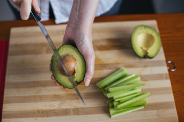 Wall Mural - Female chef cutting avocado in a home kitchen