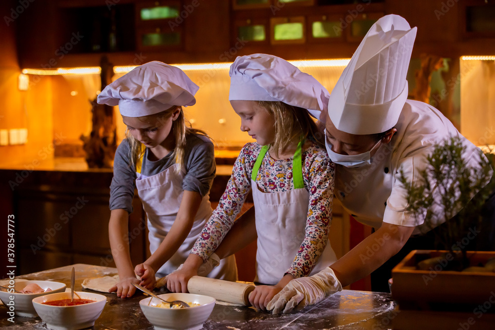 Kid cooking class. Two little girls and teacher chef in kitchen during ...