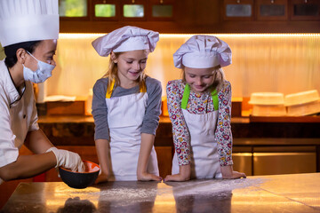 Wall Mural - Kid cooking class. Two little girls and teacher chef in kitchen during master class learning how to make pizza