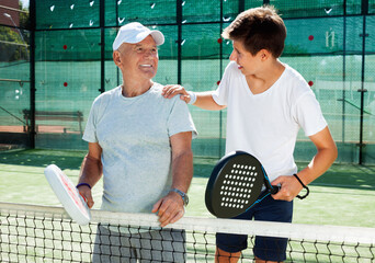 older man and a young man talking on court playing paddle