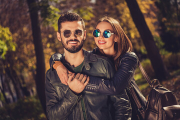 Poster - Photo of charming positive couple girl hug piggyback her boyfriend in september city park wear casual jacket