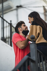 Canvas Print - Young couple with a protective mask  on a staircase smiling and kissing