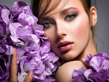 Pretty Woman With Bright Makeup. Beautiful White Girl With Purple Flowers. Stunning Brunette Girl With Big Bouquet  Of Hydrangeas. Closeup Face Of Young Beautiful Woman With A Healthy Clean Skin.