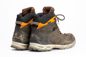 Pair of dirty brown/orange men's hiking boots with white background. Rear view, landscape format.